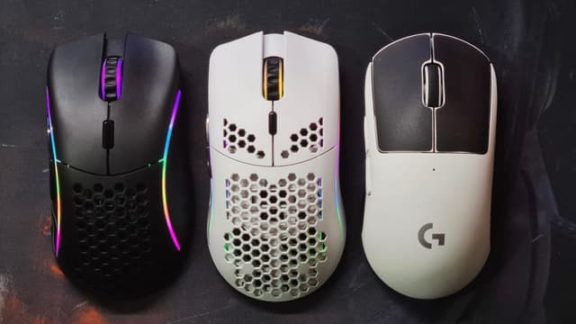 The image displays three different computer mice placed side by side against a plain background. The mouse on the left has a simple design with a solid color, the middle mouse has multiple LED lights around its edge and appears to have a modern gaming aesthetic, and the mouse on the right is predominantly white with a distinctive pattern on the scroll wheel area.