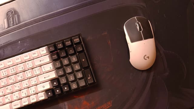 The image shows a computer workstation with a keyboard and a computer mouse. The background includes what appears to be the edge of another object, possibly a desk or table. There are no people visible in this image.